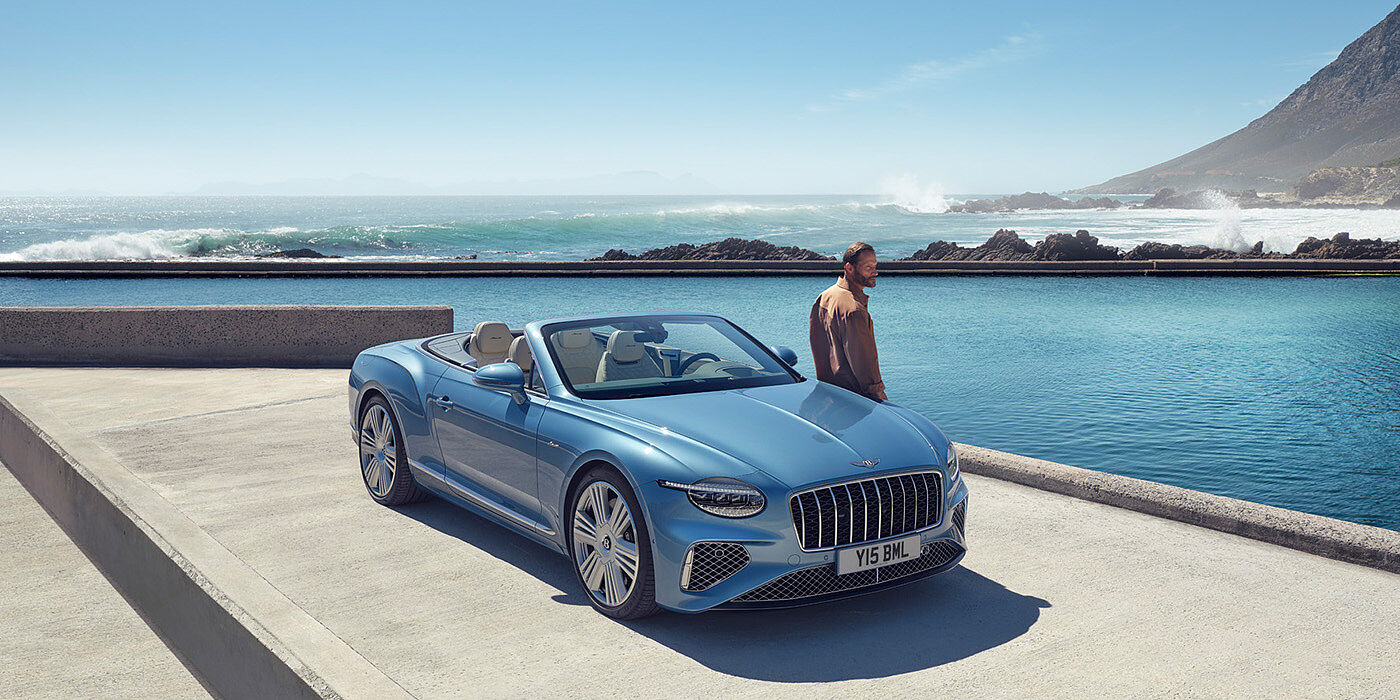 Bentley Cairo New Bentley Continental GTC Azure convertible front view in Light Windsor blue paint with 22 inch ten spoke wheels parked by the sea in the sunshine
