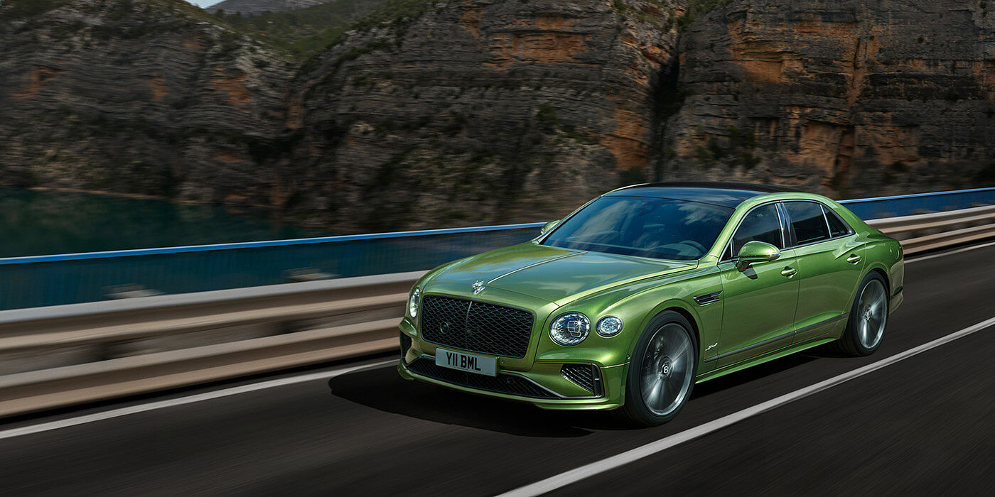 Bentley Cairo Bentley New Flying Spur Speed v8 hybrid sedan driving dynamically on a mountain road in Tourmaline Green paint