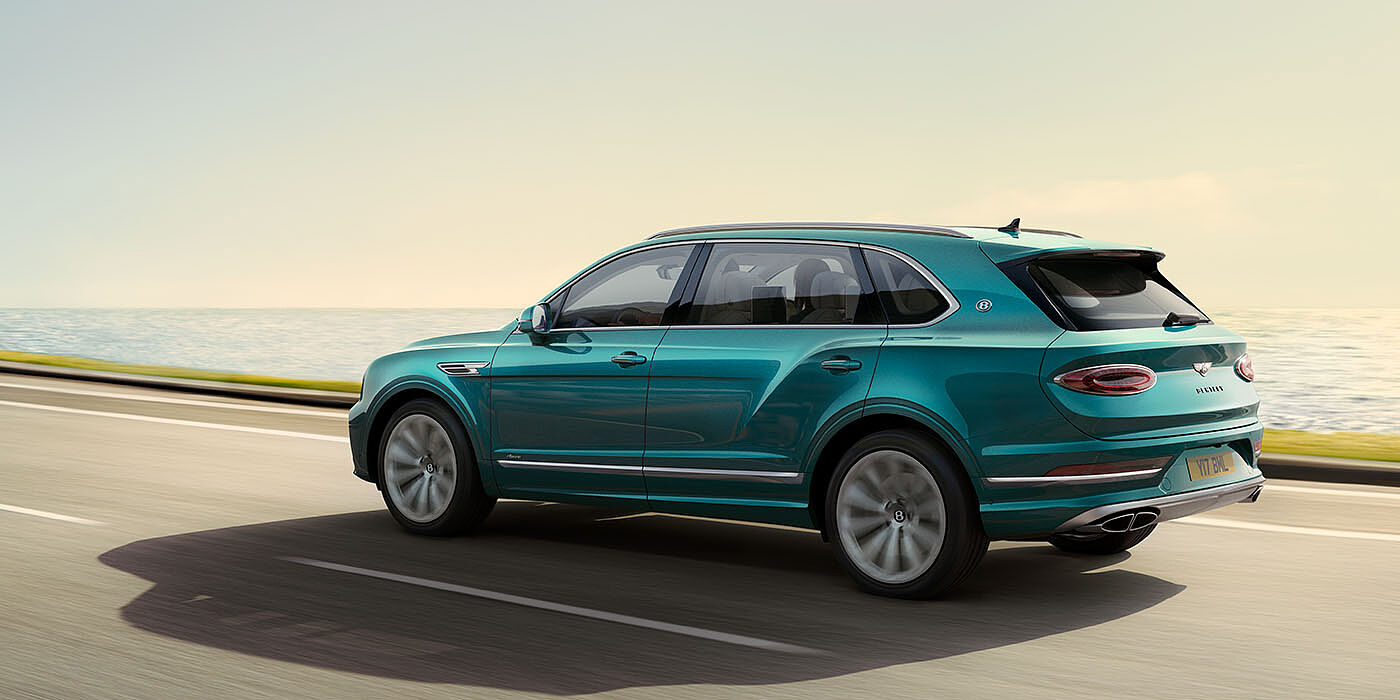 Bentley Cairo Bentley Bentayga Extended Wheelbase Azure luxury SUV rear three quarter in Topaz Blue by Mulliner paint, driving on an ocean road.