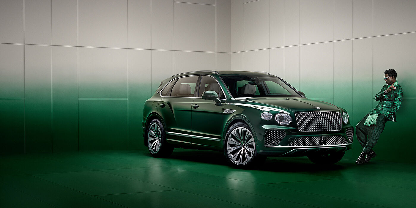 Bentley Cairo Wisdom K leans against wall next to Bentley Bentayga Extended Wheelbase Atelier Edition SUV in Light Emerald green paint