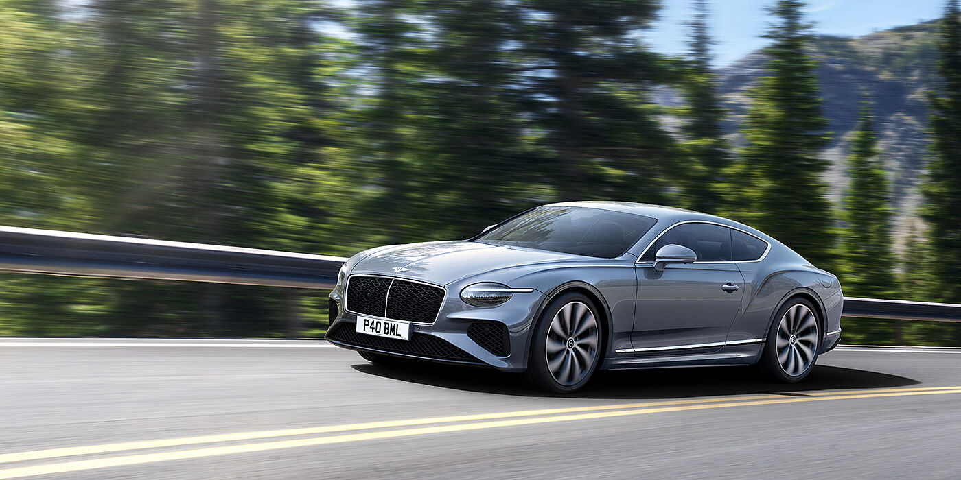 Bentley Cairo New Bentley Continental GT coupe in Silverlake paint and 22 inch ten-spoke wheels, driving dynamically on a tree-lined road in the sunshine