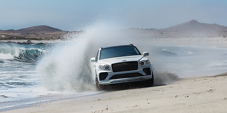 Bentley Cairo Bentley Bentayga Speed SUV facing front in Snow Quarts Pearlescent white paint driving dynamically on beach