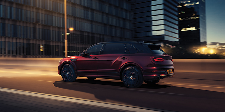 Bentley Cairo Bentley Bentayga Extended Wheelbase Mulliner SUV in Cricket Ball red paint driving dynamically in city at night